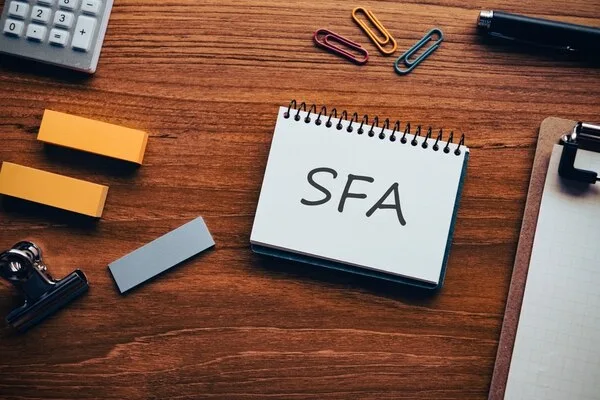 SFAと書かれたノートと営業事務用具が机上に置かれた風景
