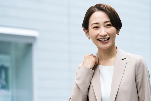 ビジネススーツを着た女性が笑顔で肩に手をかけている