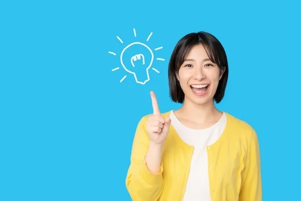 黄色いカーディガンの女性が指を指し、背後に電球のアイコン