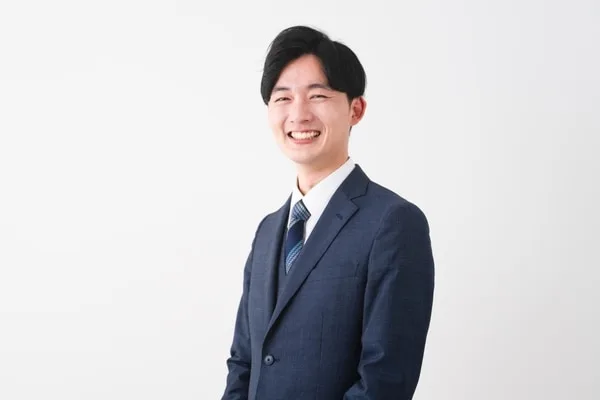 紺色のスーツとネクタイを着た笑顔の男性営業担当者