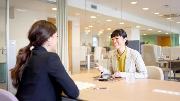 オフィスのデスクで向かい合う2人のビジネスウーマンの商談風景