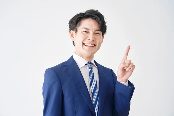 紺スーツとストライプネクタイの男性がポイントジェスチャーをしている