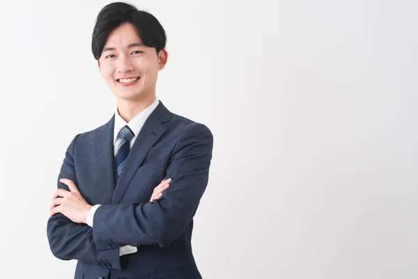 腕を組んで笑顔で立つビジネススーツ姿の男性