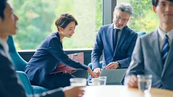 営業担当者がノートパソコンを囲んで相談している様子
