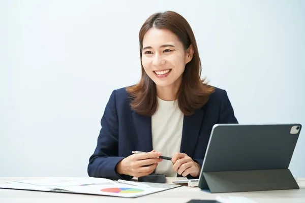タブレットとグラフ資料を前に微笑む女性