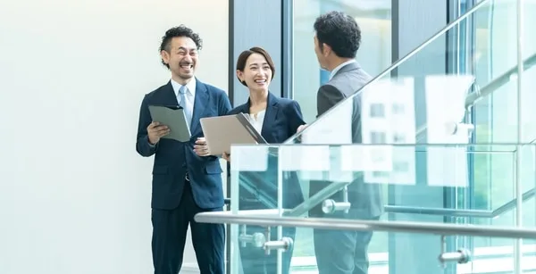 タブレットを持ちながら打ち合わせをする3人のビジネスパーソン