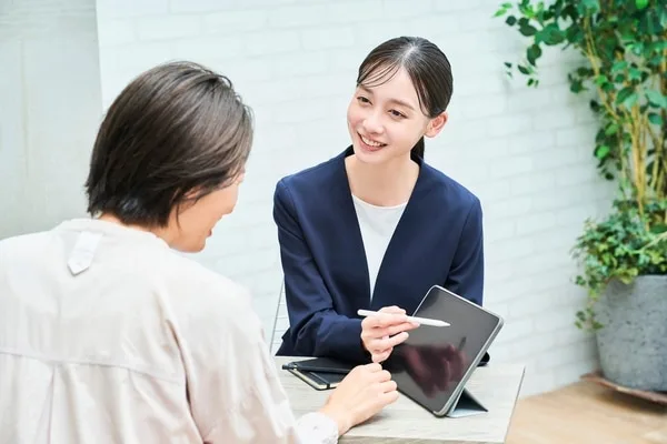タブレットを使用しながら顧客と商談する営業女性