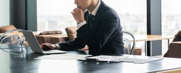 ノートパソコンを前に思案する営業担当者