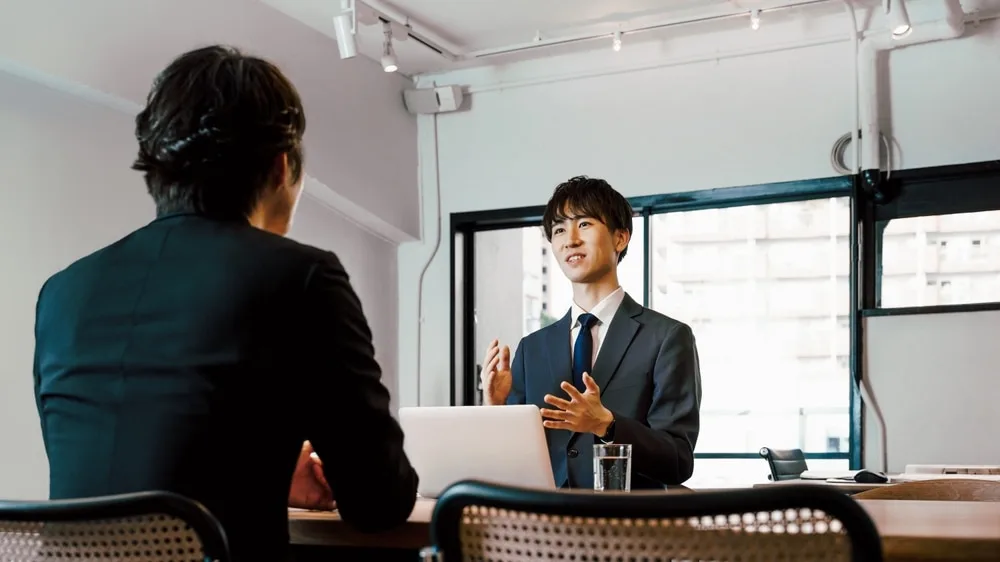 オフィスでノートパソコンを前に商談する二人のビジネスパーソン
