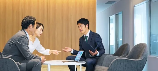 営業担当者がノートパソコンを使いながら顧客と商談している会議室