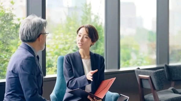 ビジネスビルのオフィスで資料を手に打ち合わせする男女