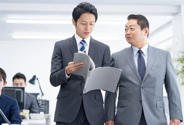 書類を確認しながら会話するスーツ姿の男性2人