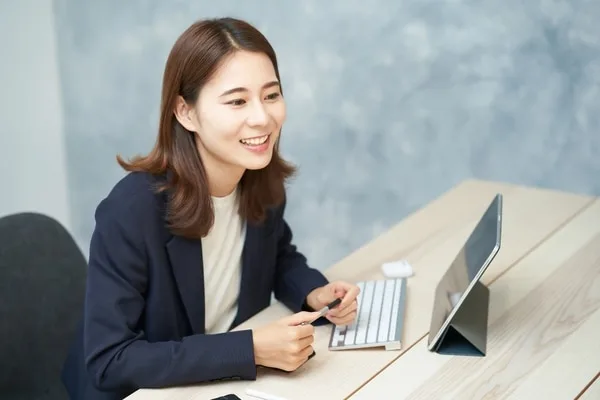 ビジネスカジュアル姿の女性がデスクでキーボード操作