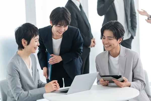 ビジネスカジュアルの男女がノートパソコンとタブレットで協力