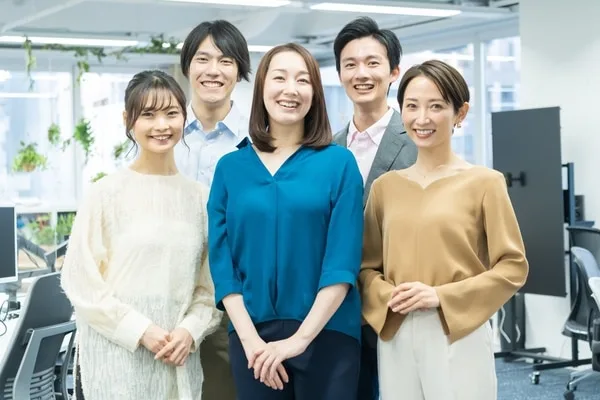 明るいオフィス空間で笑顔を見せる5人のビジネスパーソン