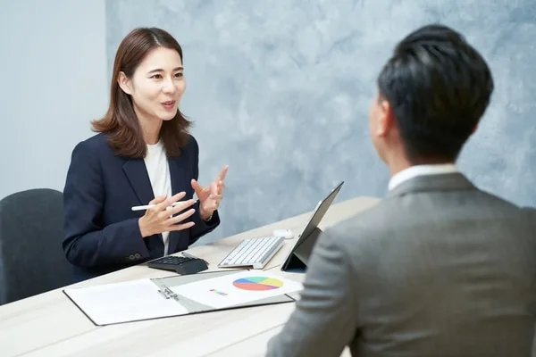 ビジネスウーマンと男性がノートパソコンと資料を前に打ち合わせ