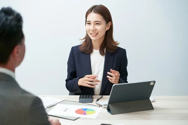 タブレットを前に商談で説明する女性