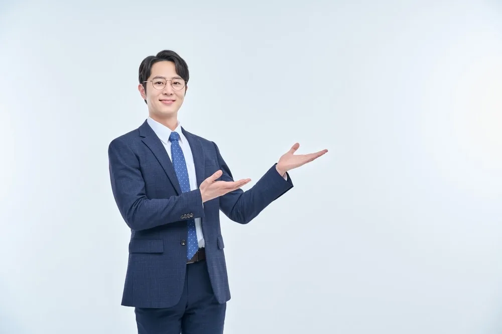 紺色スーツを着た男性営業担当者が両手で案内する仕草