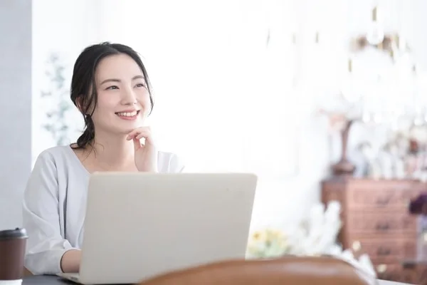 ノートパソコンを前にして考える女性