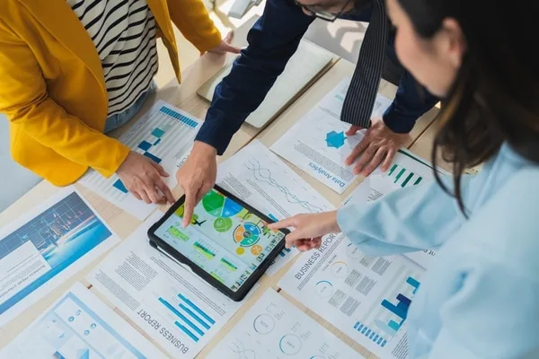 タブレット画面のグラフを指差しながら営業データを確認するチーム