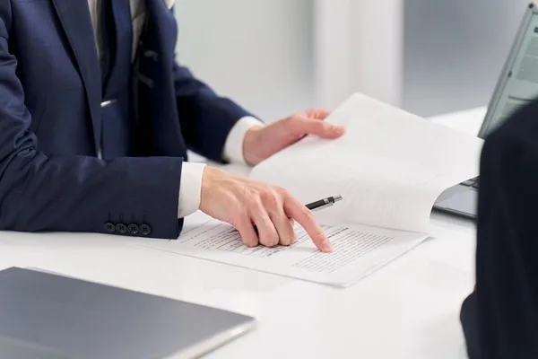 ペンを持ち書類を指し示すスーツ姿の人物
