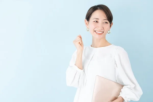 白いシャツの女性がノートパソコンを持つ笑顔