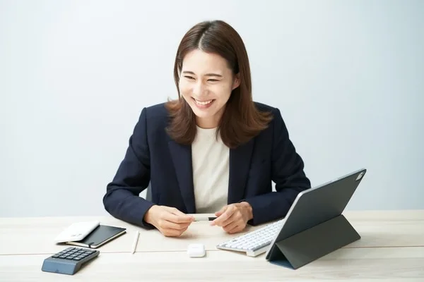 紺色ジャケットの女性がタブレットの前で笑顔