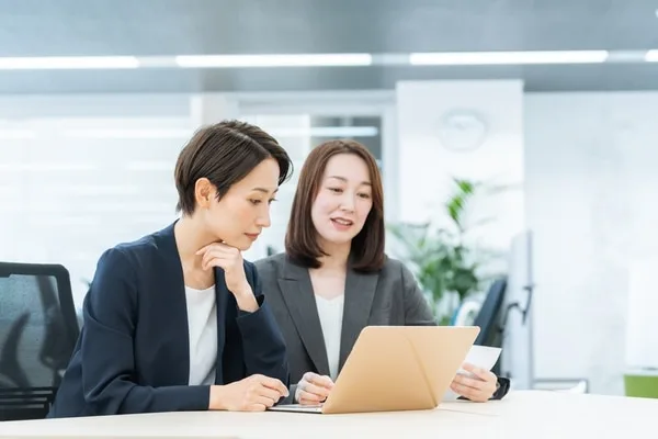 ノートパソコンを前に打ち合わせする二人の女性ビジネスパーソン