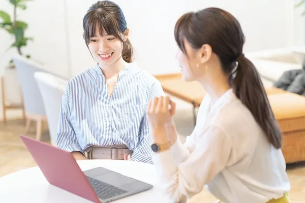 ノートパソコンを前に打ち合わせする女性営業パーソン
