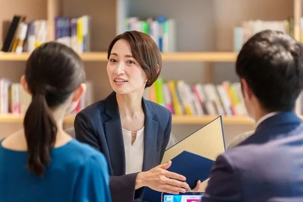 書類を持ちながら営業担当者と面談する女性マネージャー