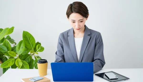 青いノートパソコンを操作するビジネス女性とオフィス環境