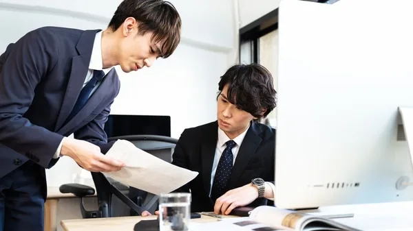 書類を確認しながら打ち合わせを行うビジネスマン二人