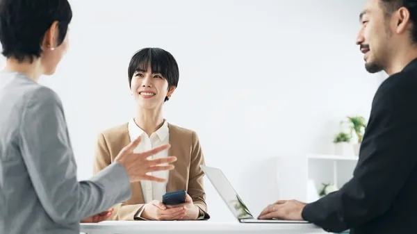 営業チームが会議テーブルでスマートフォンを使い打ち合わせ