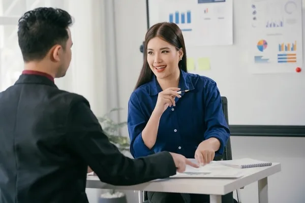 営業担当者と顧客のオフィス商談、背後にグラフとチャート表示