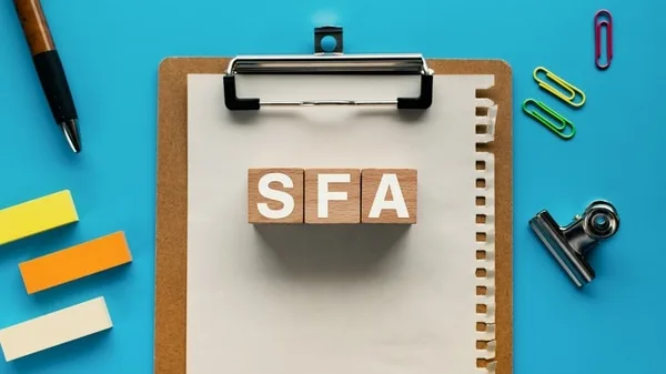 SFAと書かれた木製ブロックとペン、付箋、クリップが机上に配置された風景
