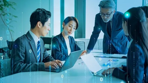 ビジネスマンらがデジタルデータを囲んで打ち合わせしている様子
