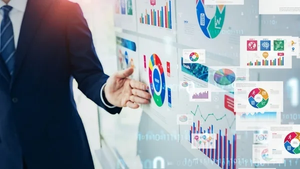 ビジネスマンが営業データとグラフを指差しながら提示
