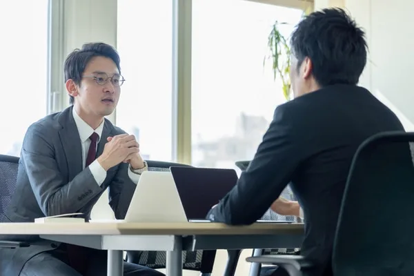 オフィスで向かい合って打ち合わせをする二人のビジネスマン