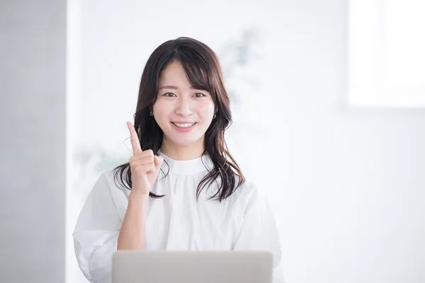 ノートパソコンの前で人差し指を立てる女性