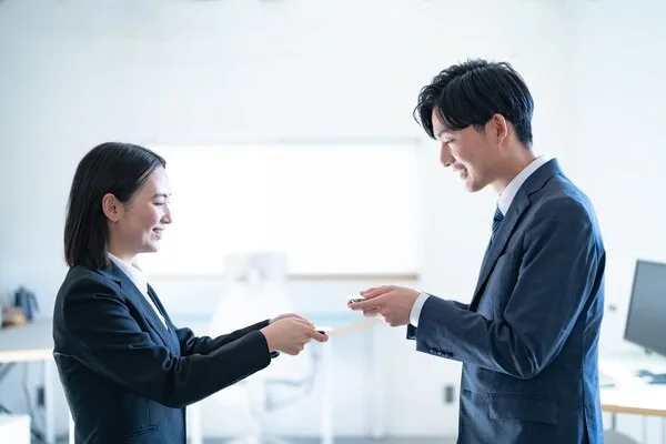 名刺交換をする男女のビジネスパーソン