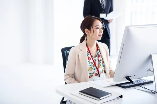 IDバッジ着用の女性がモニター画面を見つめている