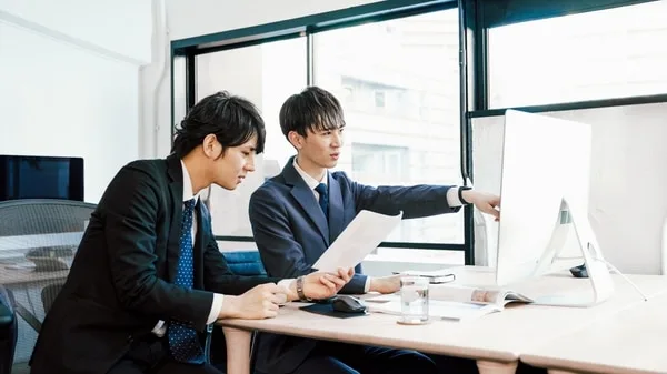 オフィスで営業資料を確認する二人のビジネスマン