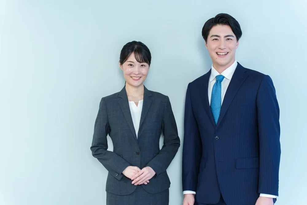 笑顔で立つ男性営業担当者と女性営業担当者