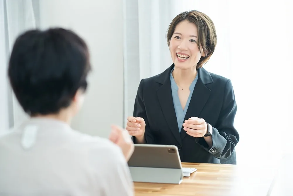 タブレットを前に顧客と笑顔で話す女性