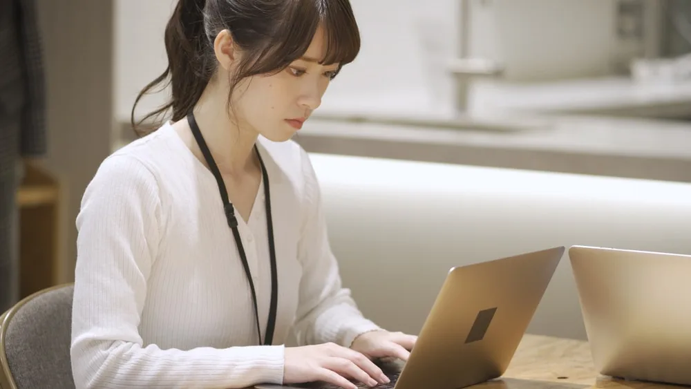 ノートパソコンで作業する女性営業スタッフ