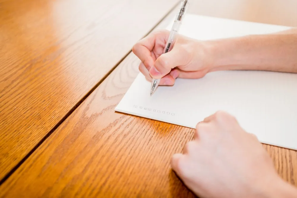 ペンで白い紙に書き込む手元