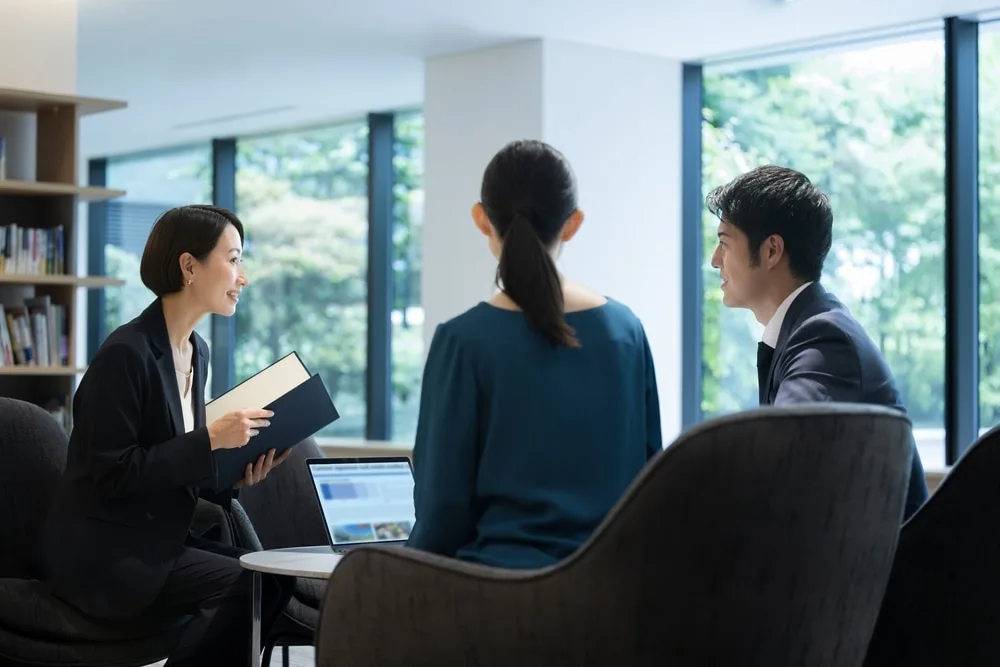 オフィスで営業担当者がノートパソコンと資料で商談打ち合わせ