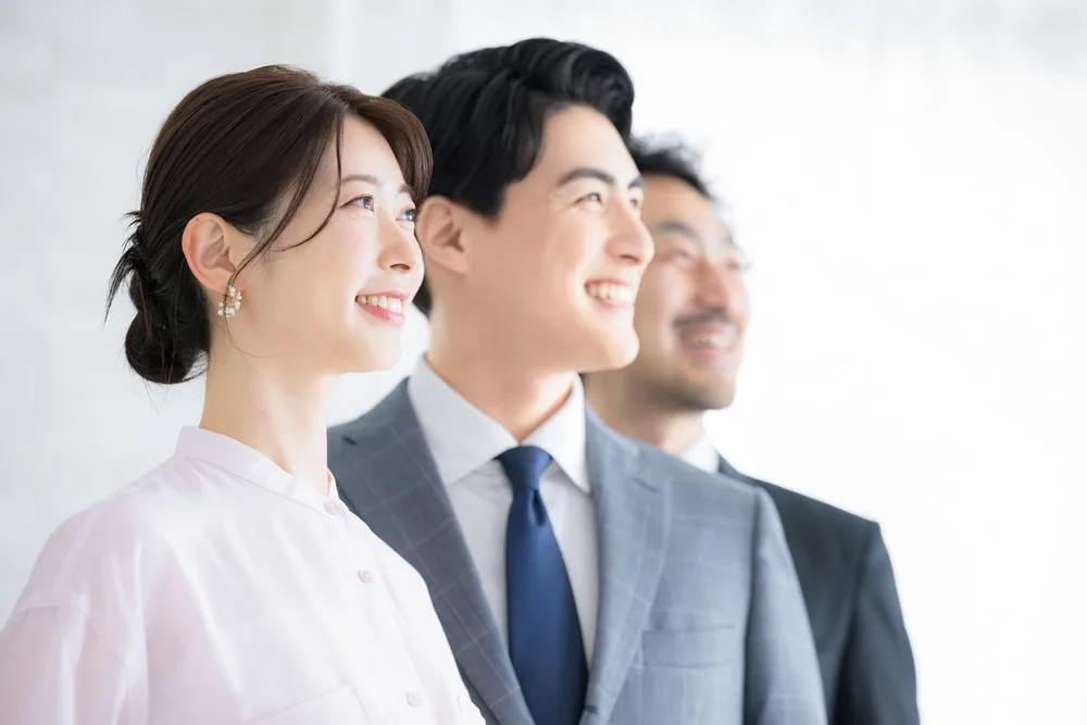 笑顔で上方を見つめるビジネスパーソン3人