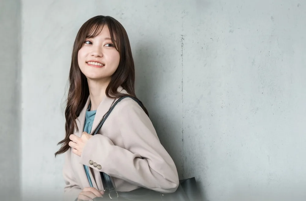 笑顔でバッグを肩にかける女性営業スタッフ