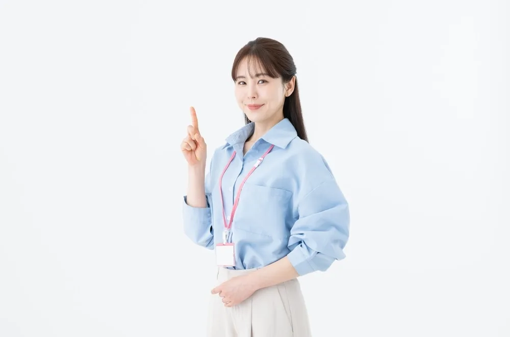 青いシャツにIDカードをかけた女性が指を立てて指示するポーズ
